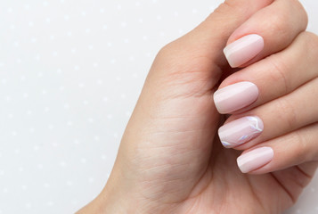 Beautiful groomed woman's hands with feminine nails on the light gray background.