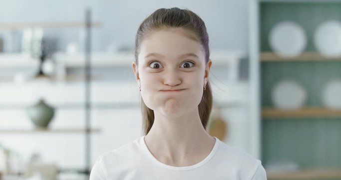 FIXED Portrait of little cute Caucasian girl doing silly funny face, looking into camera. 60 FPS Slow Motion, 4K RAW graded footage
