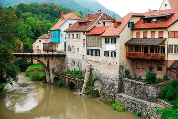 Fototapeta na wymiar Capuchin's Bridge (also known as The Stone Bridge) in Skofja Loka, Slovenia. Originally built in the 14th century, this carved stone bridge was restored in 1888