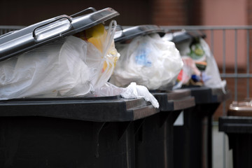 Vollgestopfte Mülltonnen an Mehrfamilienhaus durch mehr Müll wegen Corona  - Stockfoto