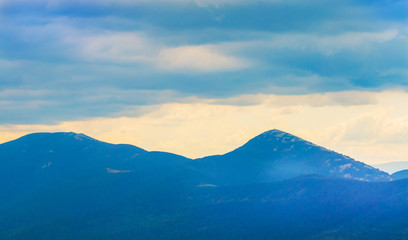 Fototapeta premium Dark clouds over blue mountains during sunset, background for design_