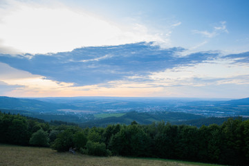 Landscape view on meadow with blue sky with many clouds and forest close to city Valasske Mezirici captured during summer late time.