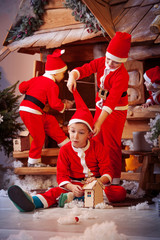 A group of four children in a Christmas hat and costumes with gifts near a fabulous house