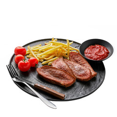 Gourmet medium rare beefsteak with French fries and fresh cherry tomatoes on a black plate with fork and knife isolated on white background. Close-up studio shot.