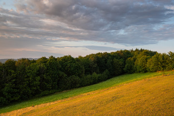 Obraz premium Meadow landscape countryside view with blue sky with many clouds sun light and forest close to city Valasske Mezirici captured during summer late time from hill.