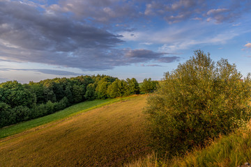 Obraz premium Meadow landscape countryside view with blue sky with many clouds sun light and forest close to city Valasske Mezirici captured during summer late time from hill.