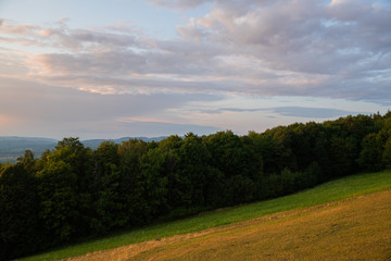 Obraz premium Meadow landscape countryside view with blue sky with many clouds sun light and forest close to city Valasske Mezirici captured during summer late time from hill.