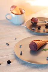  Homemade chocolate ice cream in waffle cones, berries on a wooden table, healthy dessert