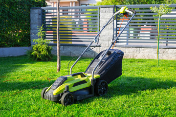 Lawn mower cutting green grass in backyard