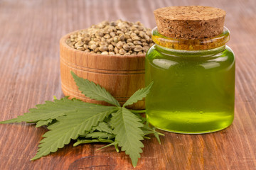 cannabis oil with cannabis seeds and leaves on wooden background