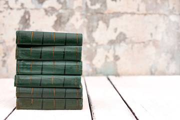 Stack of old ancient shabby books on a white wooden background.