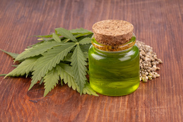cannabis oil with cannabis seeds and leaves on wooden background