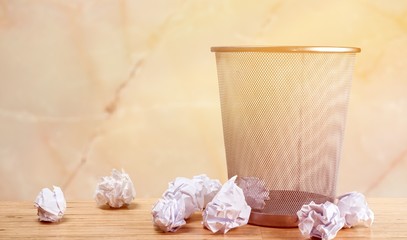 Trash can with paper sheets on wooden table
