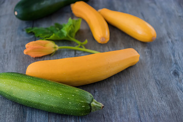 Yellow and green zucchini on a gray wooden background.