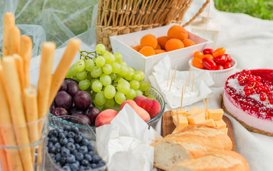 Picnic at the park on the grass: tablecloth, basket, food and accessories, top view