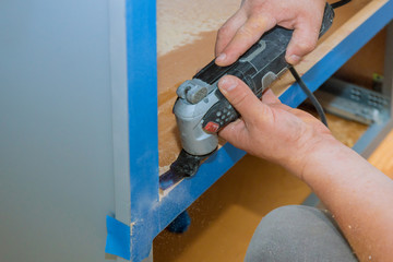 Contractor using oscillating multi functional cutting tool for handyman cut hole in kitchen...
