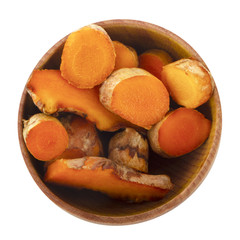 heap of turmeric slices in wooden cup isolated on white. top view