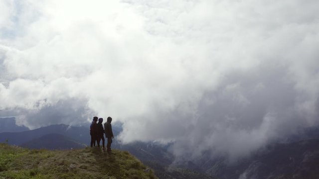The four people standing on a mountain on a cloud background