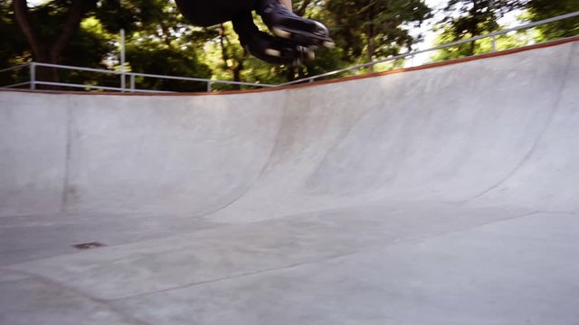 Close up of professional young man make a 360 trick on ramp. Aggressive in-line skates on roller skater feet.Roller blader wearing professional inline skates in skate park. Slow motion