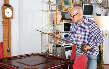 Portrait of mature man choosing vintage goods at antiques shop