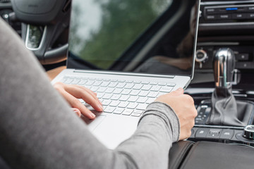 woman watching and using laptop while sitting on driver's seat in car. Crop image. Concept.