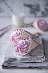 Ice-cream like pink handmade zephyr in waffle cones decorated snow sugar powder on light background with milk