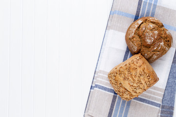 Gold rustic crusty loaves of bread and buns on wooden background. Still life captured from above top view, flat lay.