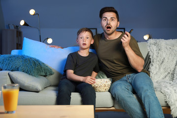 Father with son watching scary movie in evening