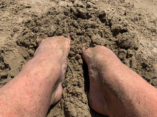 Sandy feet on a beach by the sea