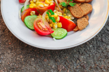 salad with vegetables and crackers (tomato, cucumber, breadcrumbs, corn, salad dressing). food background. top view, copy space