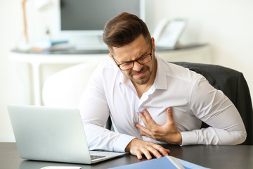 Young businessman having heart attack in office