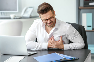 Fototapeta premium Young businessman having heart attack in office