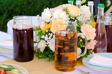 Cold drinks, Juices and water on a banquet table decorated of flowers bouquet in restaurant.
