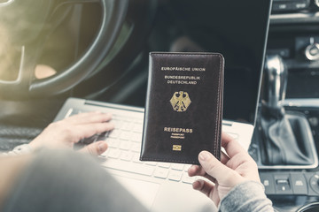 Woman in the car with laptop and germany passport. Travel concept.