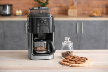 Modern coffee machine with cookies on table in kitchen