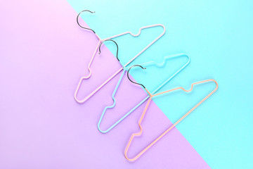 Clothes hangers on color background