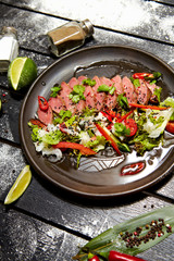 Asian dish on a black plate. Veal salad