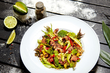 Asian dish on a white plate. Salad with roast duck, mango, avocado and sesame seeds