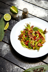 Asian dish on a white plate. Salad with roast duck, mango, avocado and sesame seeds