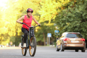 Fototapeta premium Sporty young woman riding bicycle outdoors
