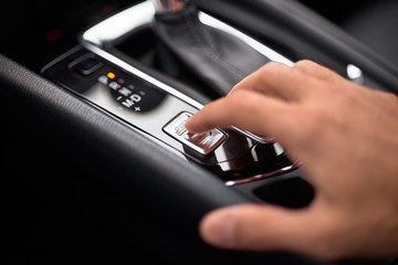 Close up on the Sport Mode button of a car. Finger pressing the button.