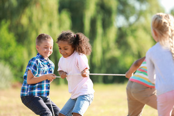 Fototapeta premium Group of little children pulling rope in park