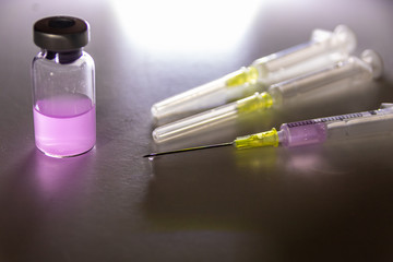 Impfstoffentwicklung: Leuchtende Spritze mit pinkfarbenem Heilmittel aus einer medizinischen Ampulle zur Therapie von Patienten mit Impfstoff und neuartigen Wirkstoffen