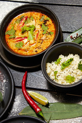 Asian dish on a black plate. Tom yum with rice