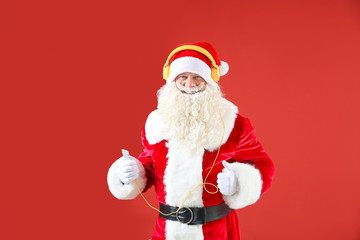 Portrait of cool Santa Claus listening to music on color background