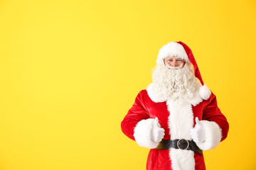 Portrait of Santa Claus showing thumb-up on color background