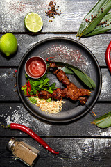 Asian dish on a black plate. Veal Satay