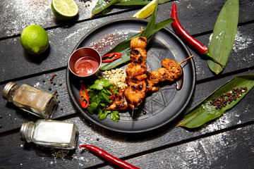 Asian dish on a black plate. Chicken Satay