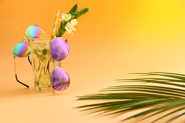 Fresh cocktail with stylish sunglasses on color background