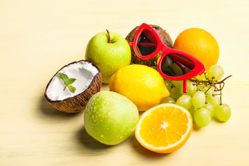 Stylish sunglasses with tropical fruits on table